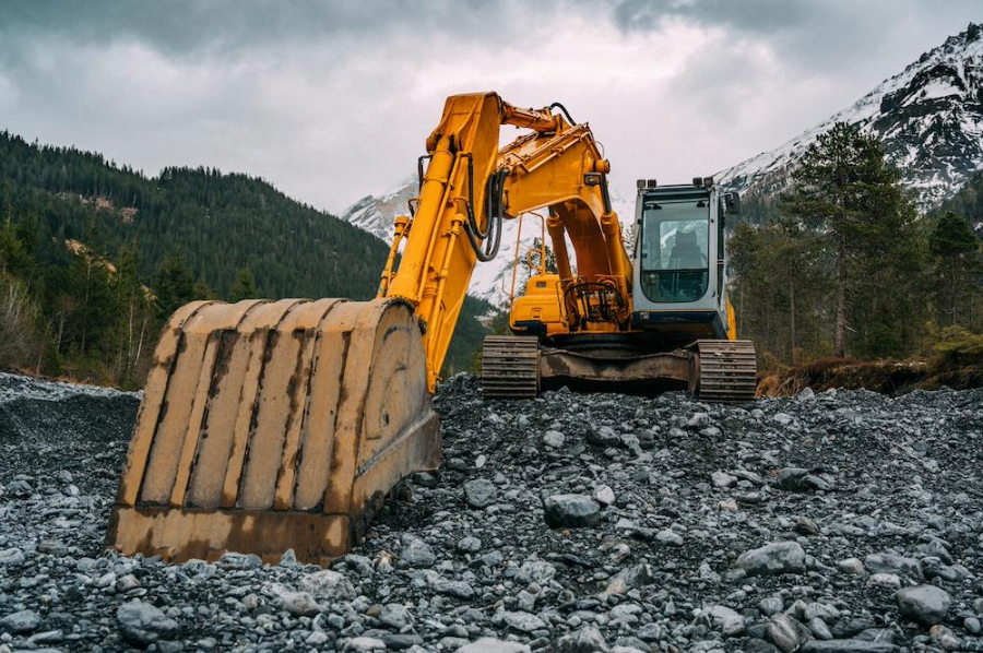 Excavator working on rocky terrain at a mountain construction site.